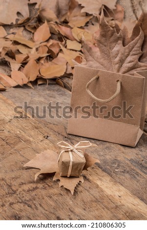 gift box, shopping bag and dried leafs on wooden surface