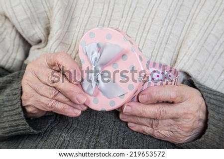 a senior person opening heart shaped gift box (close up)