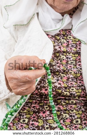 senior woman holding prayer beads to pray