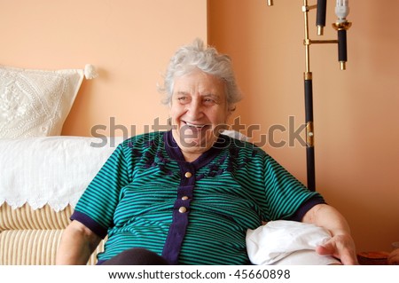 portrait of a sweet retired friendly old woman sitting on a couch