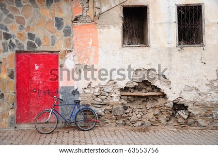 bike stands on by red door of an old building