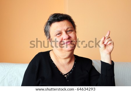 Closeup of a happy senior woman pointing upwards