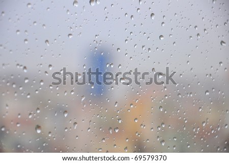 Drops of rain on a window pane, buildings in background