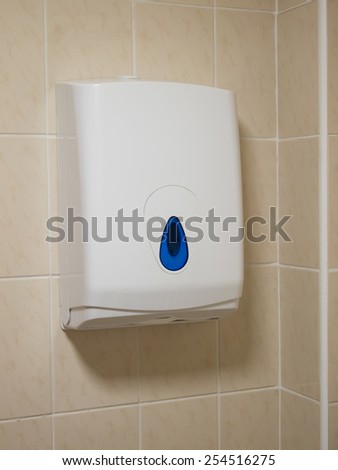 towel dispenser on toilet tiled wall