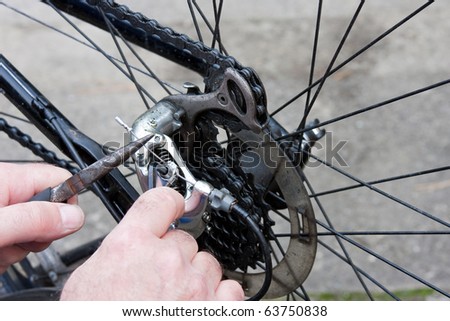 Working Hands Adjusting Bicycle Gears with Pliers and Key