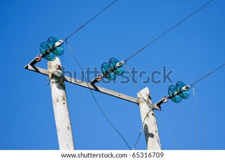 Electricity Poles with Wires and Green Glass Insulators against Deep Blue Sky