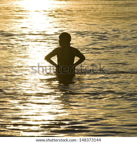 A woman swimmer in river at sunset in summer