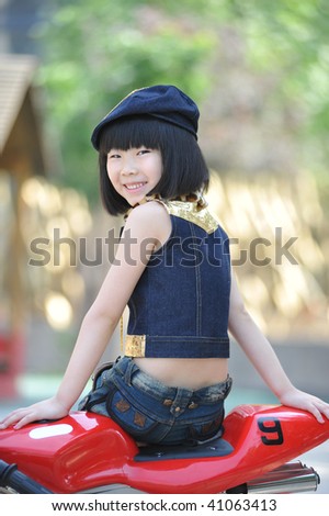 Adorable little girl sitting on the red toy motorbike.