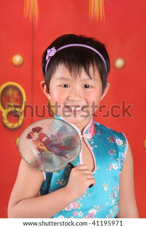The little asian girl is in Chinese style clothes with her fan.