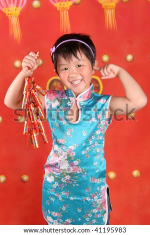 The little asian girl is in Chinese style clothes holding firecracker.