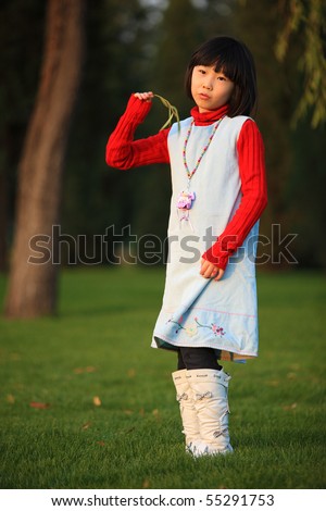 The little Chinese girl standing outside in autumn