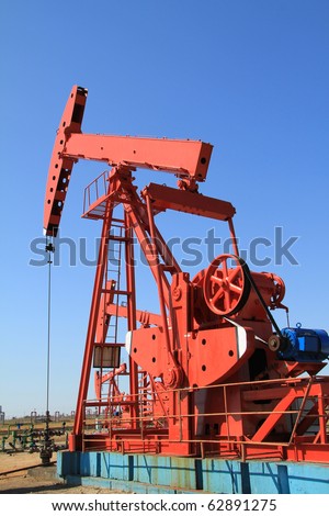 The red oil pump jack on blue sky