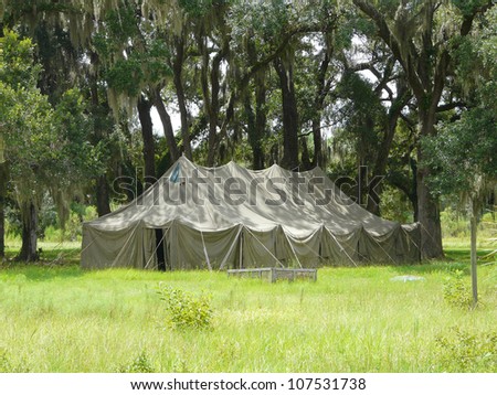 Large old tent among live oak trees with Spanish moss in a park setting.