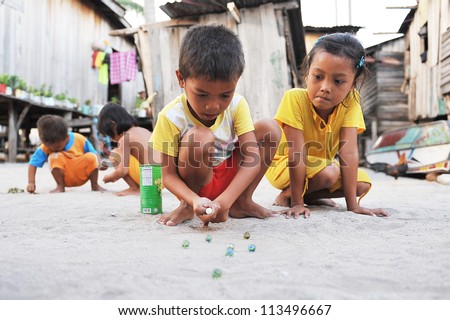 Semporna, Malaysia - July 24 : Unidentified Sea Gypsies Kids Playing Marbles On July 24, 2009 In Semporna, Sabah, Malaysia. Children Here Do Not Attend School For Lack Of Means And Resources.