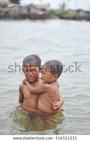 SEMPORNA, MALAYSIA - JULY 26 : Unidentified sea gypsies kid carries his brother on July 26, 2009 in Semporna, Sabah, Malaysia. Children here do not attend school for lack of means and resources.