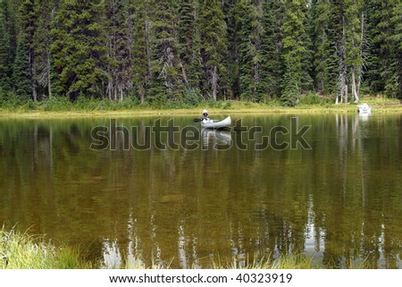 Mirror lake & a white canoe fisherman.