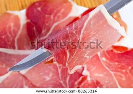 cut slices of ham with a carving knife on the plate out of focus