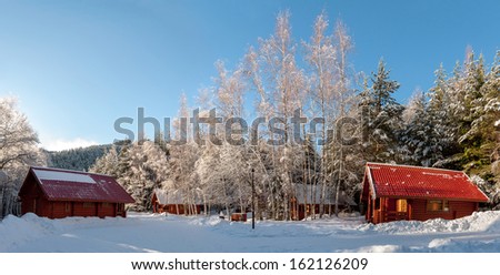 Panoramic view with two ski houses in winter forest