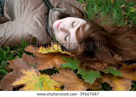 Portrait of a young beautiful ginger lying on the autumn leaves