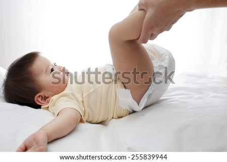 A small cute little baby girl was lying down, her diaper was being changed by her father, closeup, white background, studio