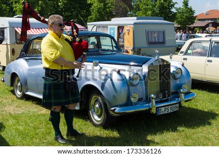 PAAREN IM GLIEN, GERMANY - MAY 19: Piper plays the Great Highland Bagpipe near the car Rolls-Royce Silver Cloud, The oldtimer show in MAFZ, May 19, 2013 in Paaren im Glien, Germany