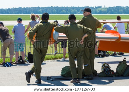 BERLIN, GERMANY - MAY 22, 2014: The pilot and mechanics near light military jet Aermacchi MB-326 stand. Catellani Group (Italy). Exhibition ILA Berlin Air Show 2014