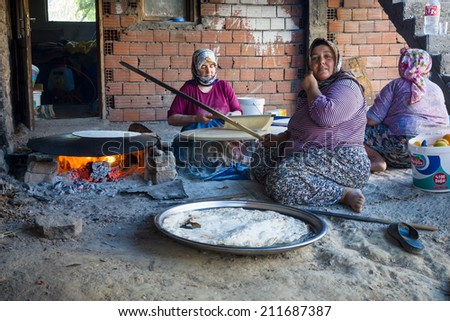EVRENLERYAVSI, TURKEY - JUNE 24, 2014: Village women prepare traditional flatbread on an open fire.