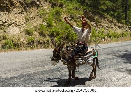 ALANYA, TURKEY - JUNE 27, 2014: Village resident entertains tourists riding on a donkey