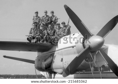 MOSCOW REGION, RUSSIA - CIRCA 1993: A group of soldiers standing on the wing of a military transport aircraft AN-24. Film scan. Large grain, circa 1993
