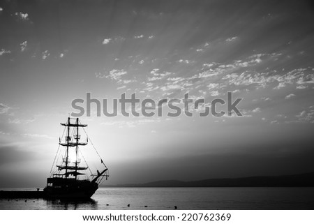 Sunset over the sea and a lone sailboat in the bay. Stylization. Black and white.