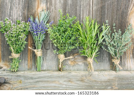 different fresh herbs posy against background of wood
