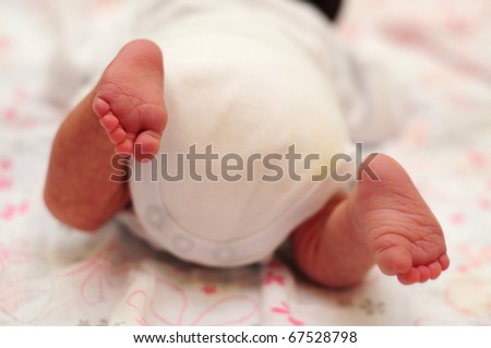 cute little new born baby\'s feet.  new born baby is trying to crawl.