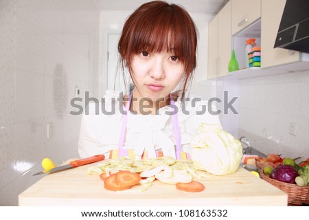 A Chinese woman is cooking on a chopping block with various kinds vegetableA Chinese woman is cooking on a chopping block with various kinds vegetable