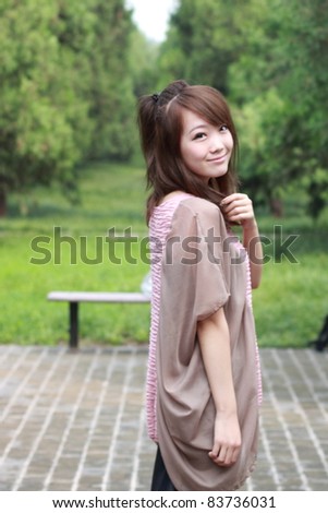 A lovely asian woman in a park’ grass plot.