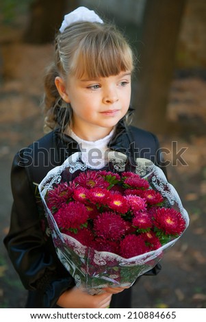 schoolgirl with a bouquet of flowers in front of school