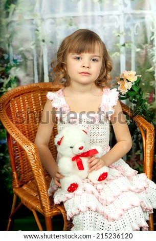 beautiful girl in knit dress with a toy in the garden