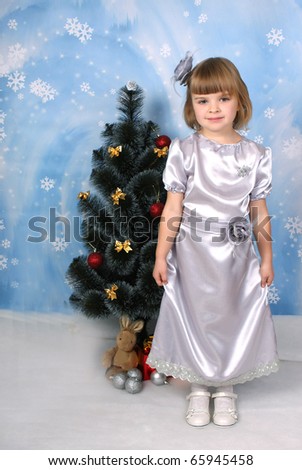 cute girl in a silver dress around Christmas tree