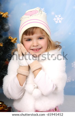 beautiful girl in a fur cape, hat and gloves around the Christmas Tree