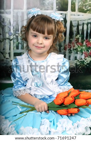 beautiful girl in a blue dress sat down with red tulips