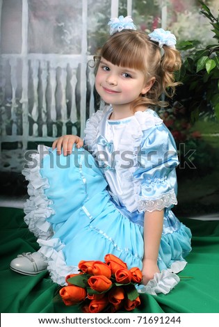 beautiful girl in a blue dress sat down with red tulips
