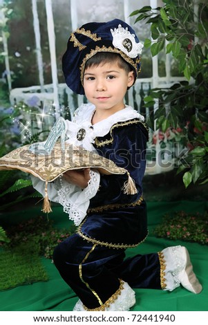 cute little boy dressed in a dark blue dress and beret on his knees and holds a crystal shoe