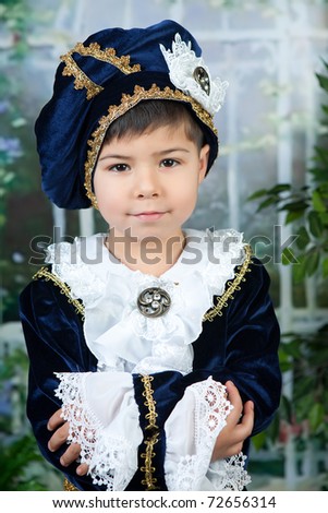 cute little boy dressed in a dark blue dress and take on the background of the garden