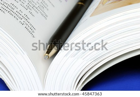 Open book with a pen isolated on blue