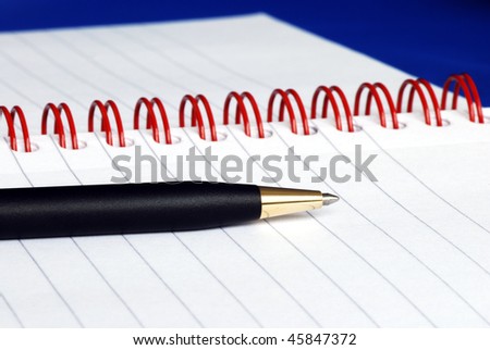 The spiral note pad with a pen isolated on blue