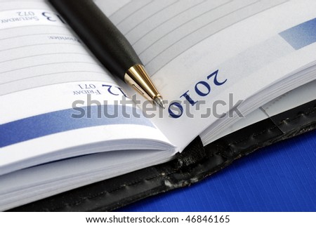 Close up view of the diary with a pen isolated on blue