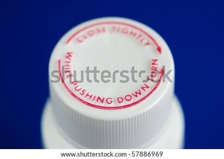 Close up view of a safety caps of a child-proof pill bottle isolated on blue