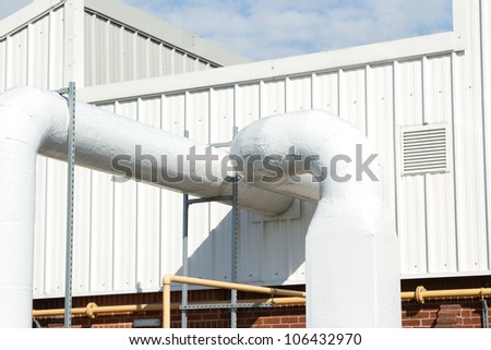 An industrial unit with a vent and large diameter air conditioning pipes.