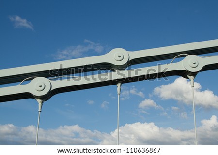 A link section of an industrial chain made of multiple steel plates bolted together, with cable attachments as part of a suspension bridge.