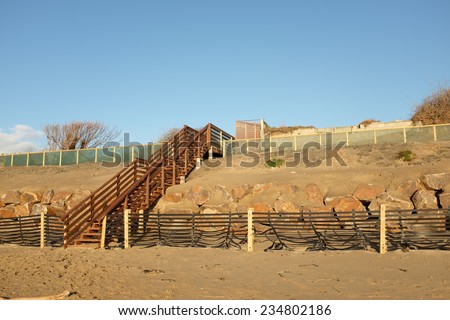A set of wooden stairs, steps, built over a constructed dune with sand drift fence, base rock and overlayed sand.