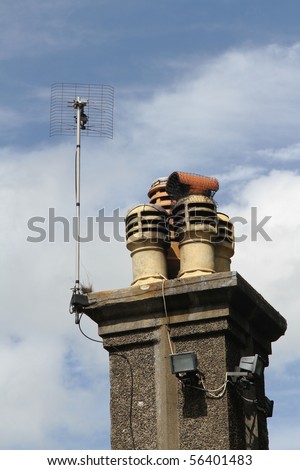 Chimney pots on a stack with tv aerial and security lights.